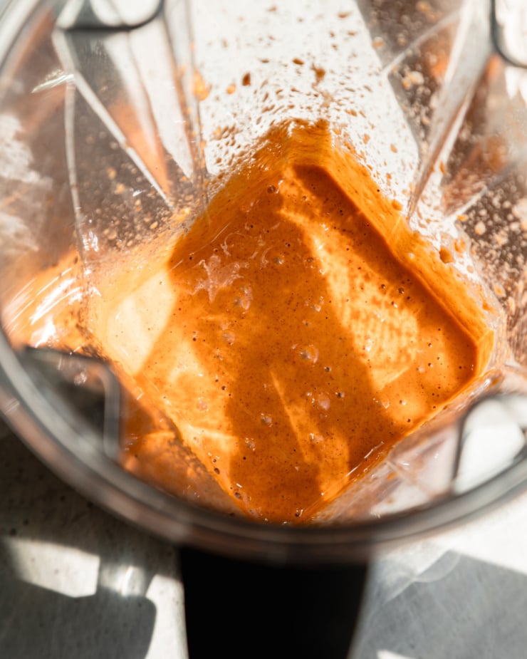 An overhead shot shows a blender pitcher with freshly blended up Gpchujang peanut dressing.