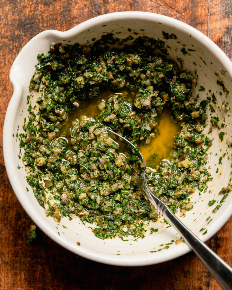 An overhead shot shows a bowl of dill pickle salsa verde with a spoon sticking out.
