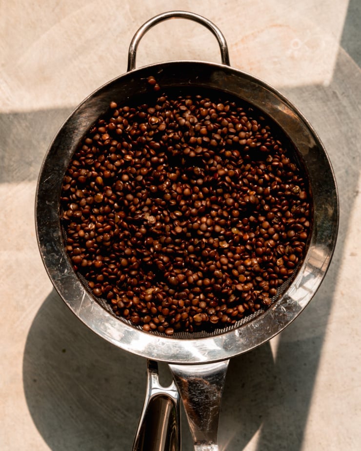 An overhead shot shows cooked black lentils in a strainer.