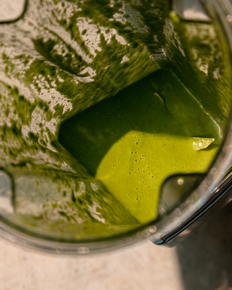An overhead shot shows basil vinaigrette in a blender pitcher.