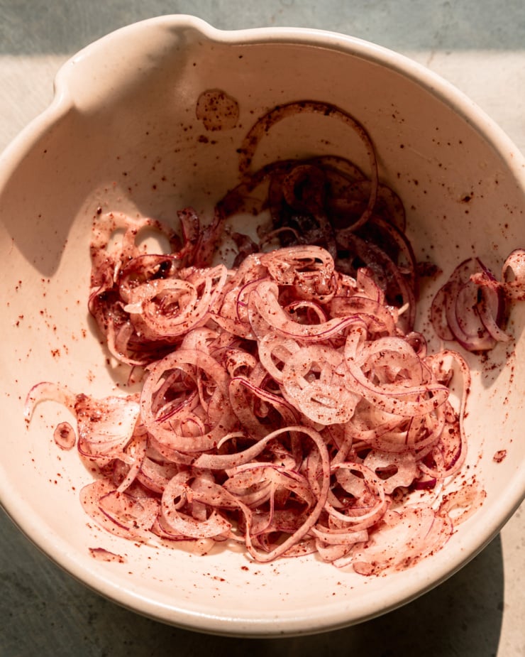 An overhead shot shows a bowl of sumac onions in direct sun light.