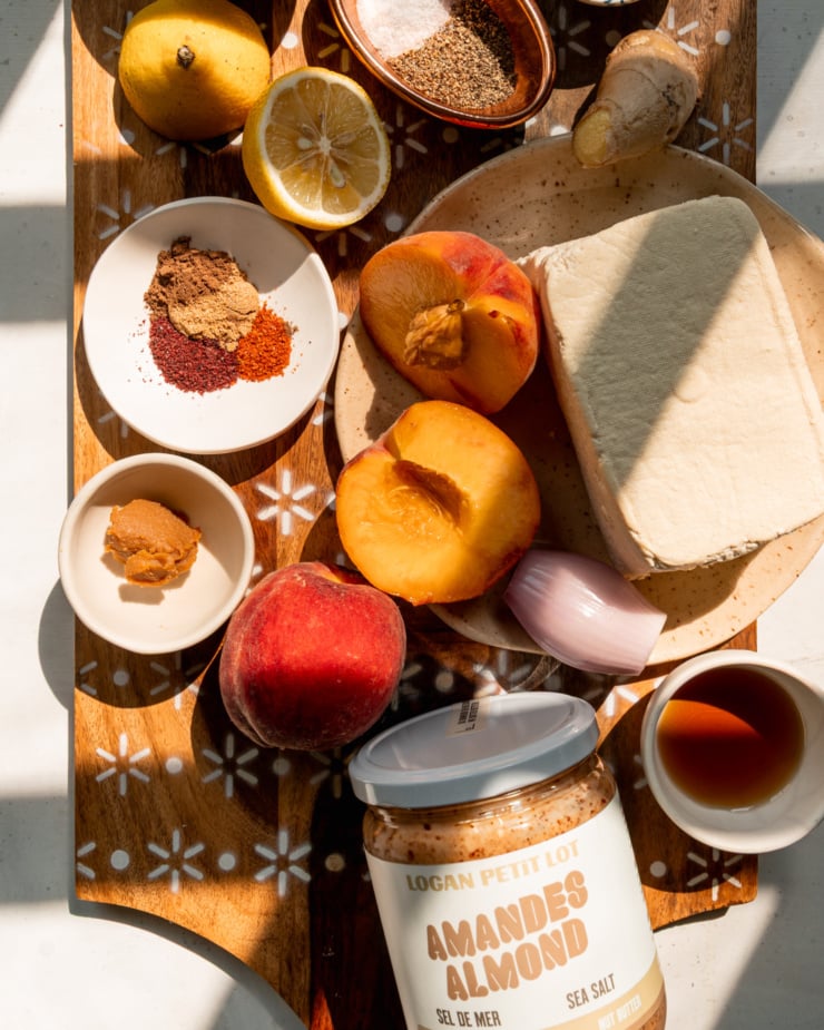 An overhead shot shows ingredients needed for a grilled tofu dish that's served with a savory and sticky peach, almond butter & miso sauce.
