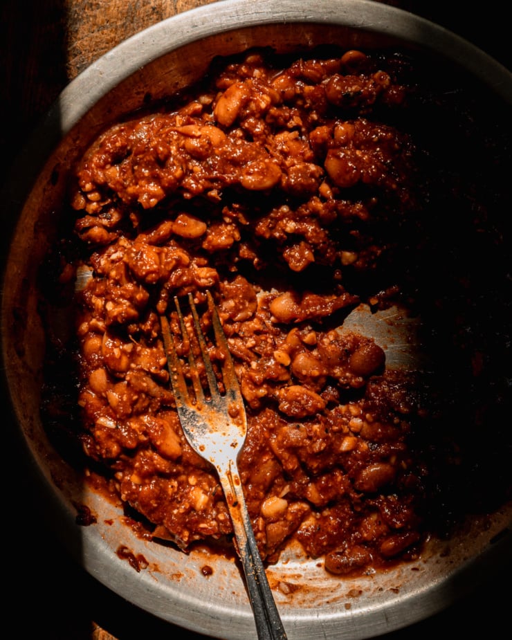 An overhead shot shows pinto beans that have been smashed up with chipotle salsa.