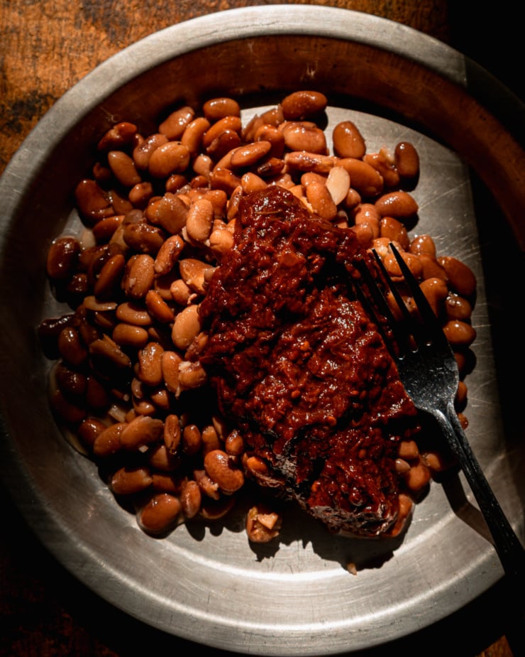 An overhead shot shows a shallow dish with pinto beans and thick chipotle salsa.