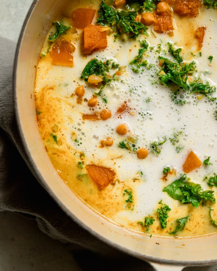 An up close, overhead shot shows coconut milk that has been freshly poured into a pot of stew.