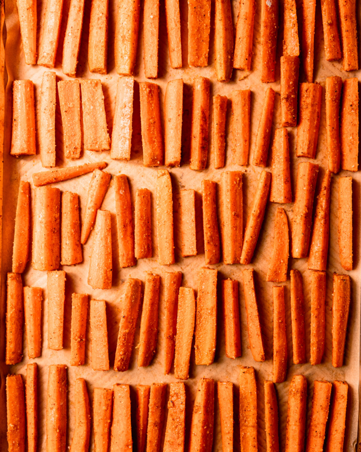 An overhead shot shows carrot sticks arranged in perfect rows on a parchment-lined baking sheet.