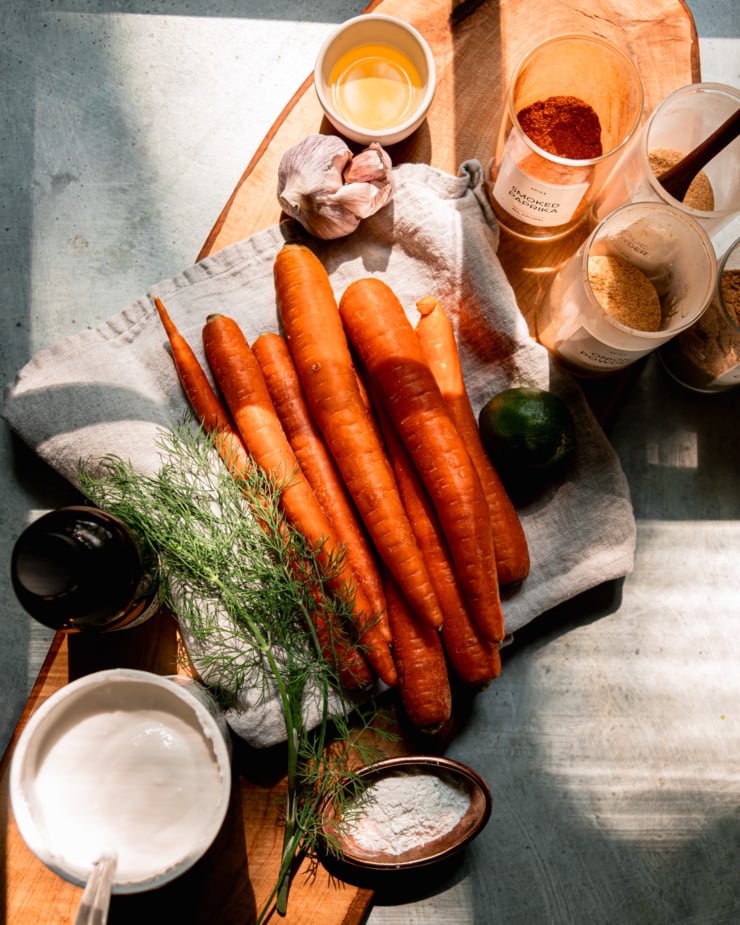 An overhead shot shows ingredients needed for oven-baked carrot fries and a creamy yogurt dip to go along with.