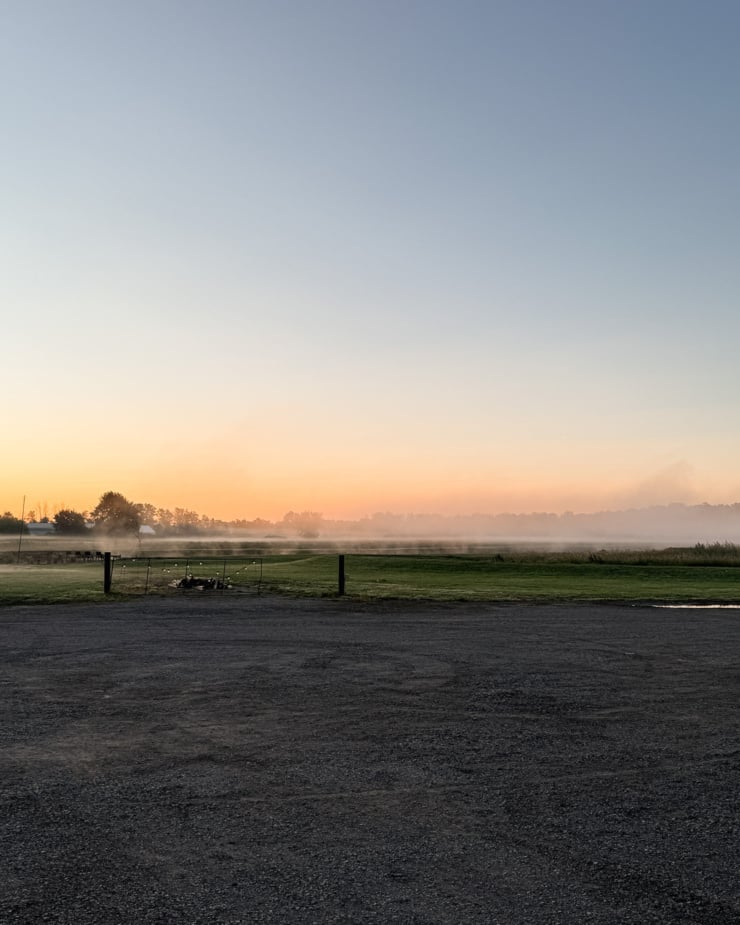 A head-on shot shows the sun beginning to rise over a farmer's field.