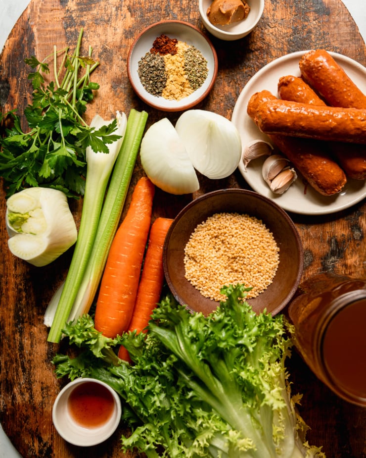 An overhead shot shows ingredients for a vegan Italian wedding soup recipe; all on a rough wooden board.