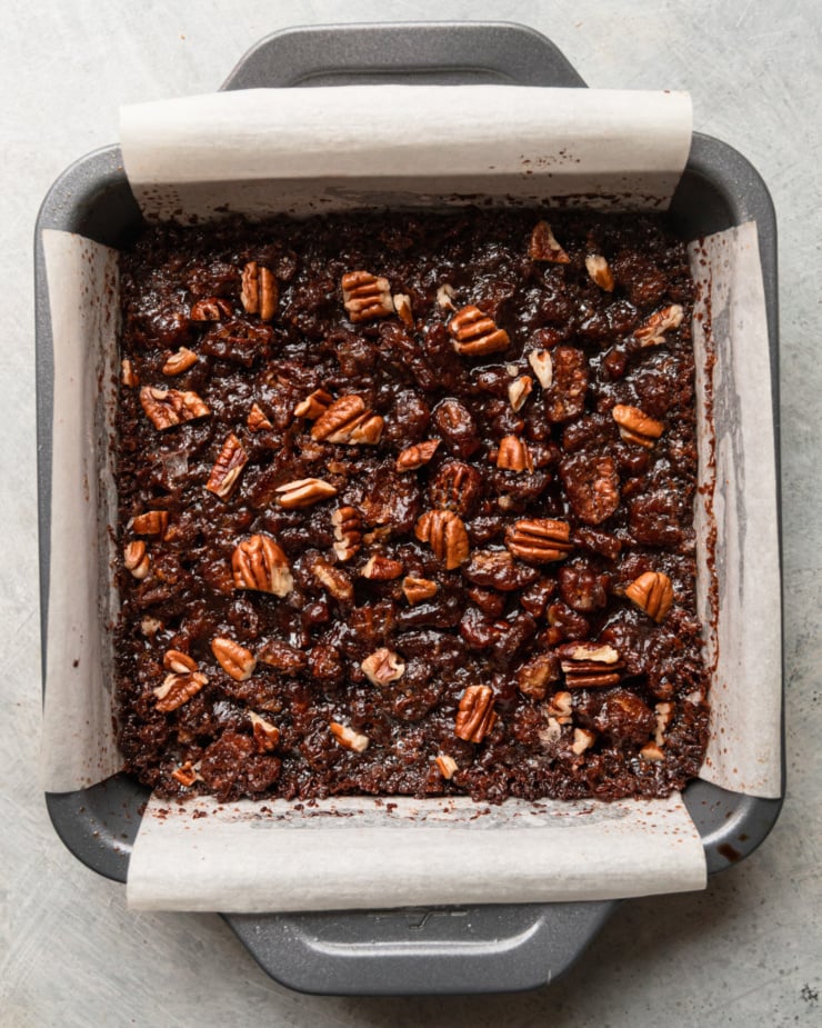 An overhead shot shows a pan of baked chocolate pecan bars.