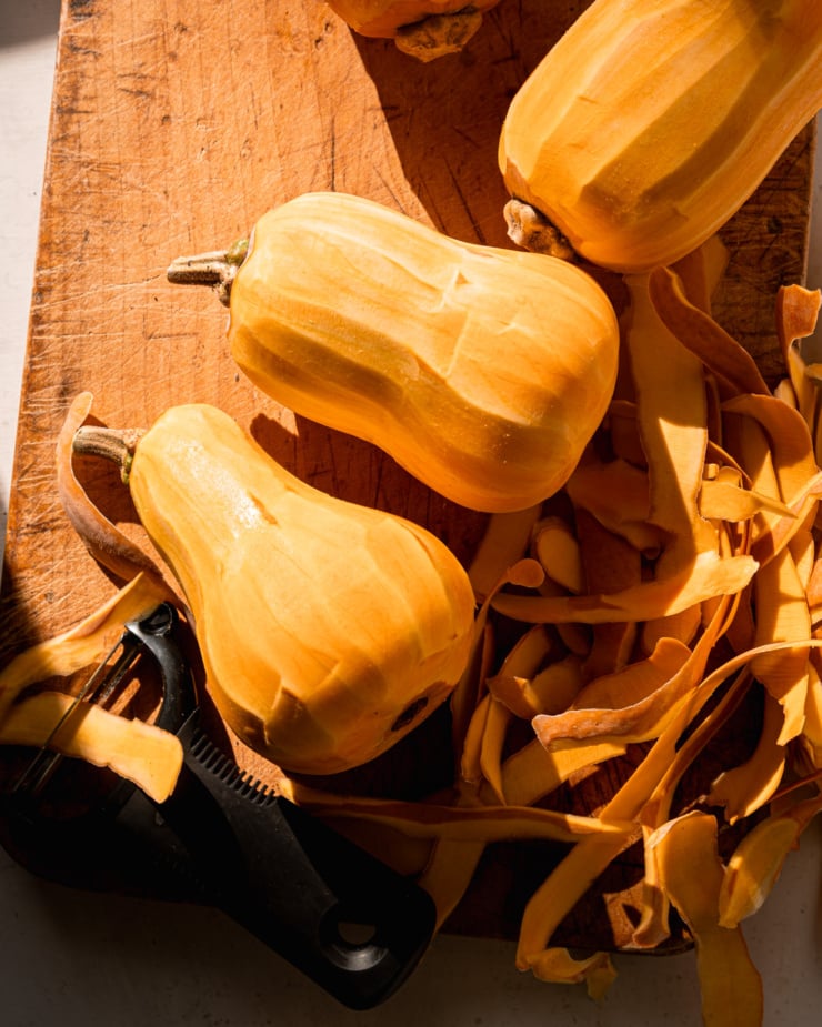 An overhead shot shows peeled honeynut squashes and a pile of peel strips on a cutting board.
