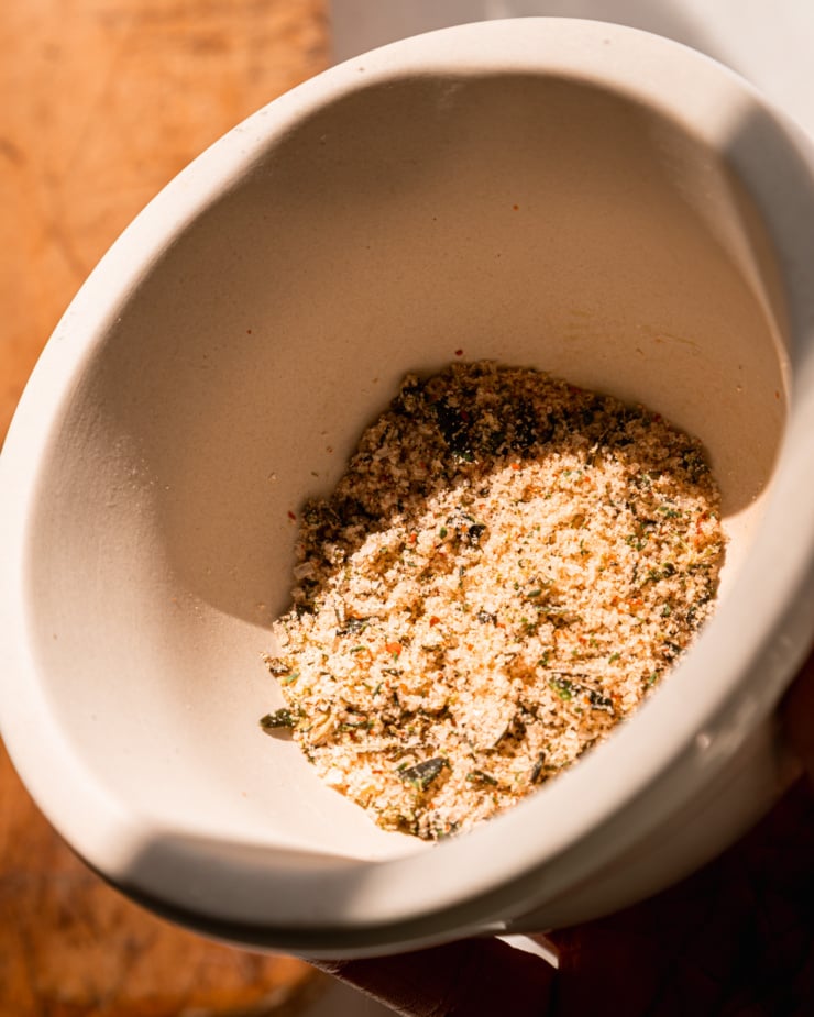 An overhead shot shows some herb salt in the mortar part of a mortar and pestle.