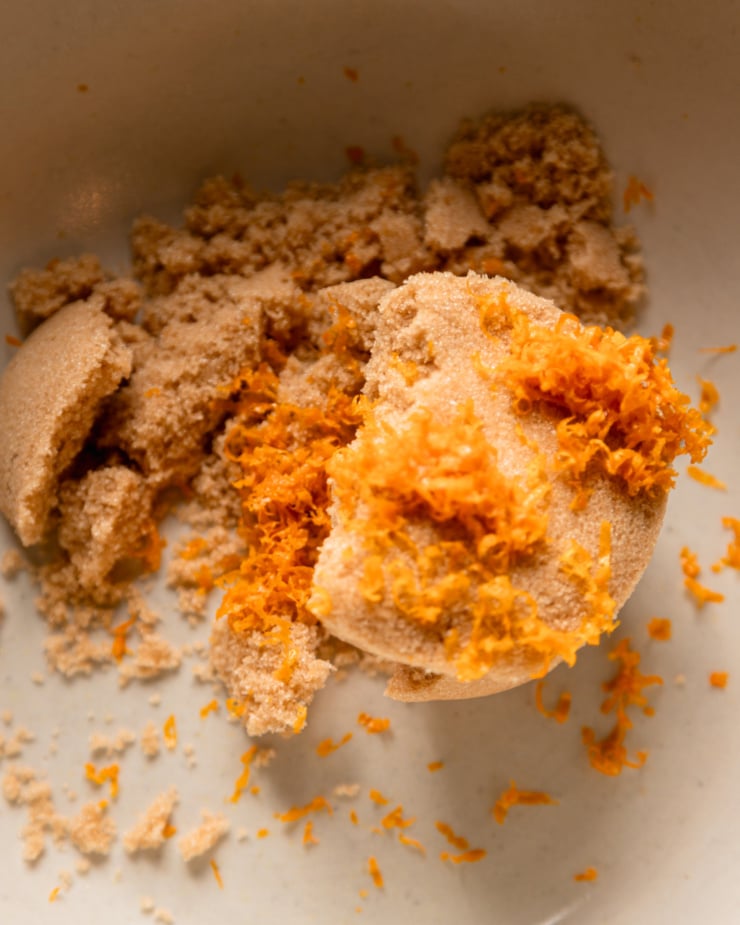 An overhead shot shows light brown sugar and orange zest in a bowl.