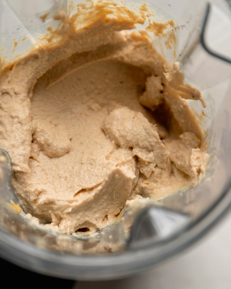 An overhead shot shows whipped up tofu and cashew ricotta in a blender pitcher.