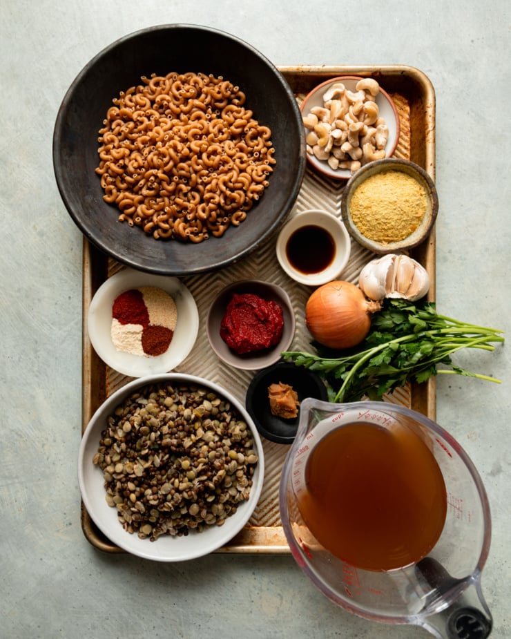 An overhead shot shows ingredients for a vegan hamburger helper-style dish with lentils and whole grain pasta.